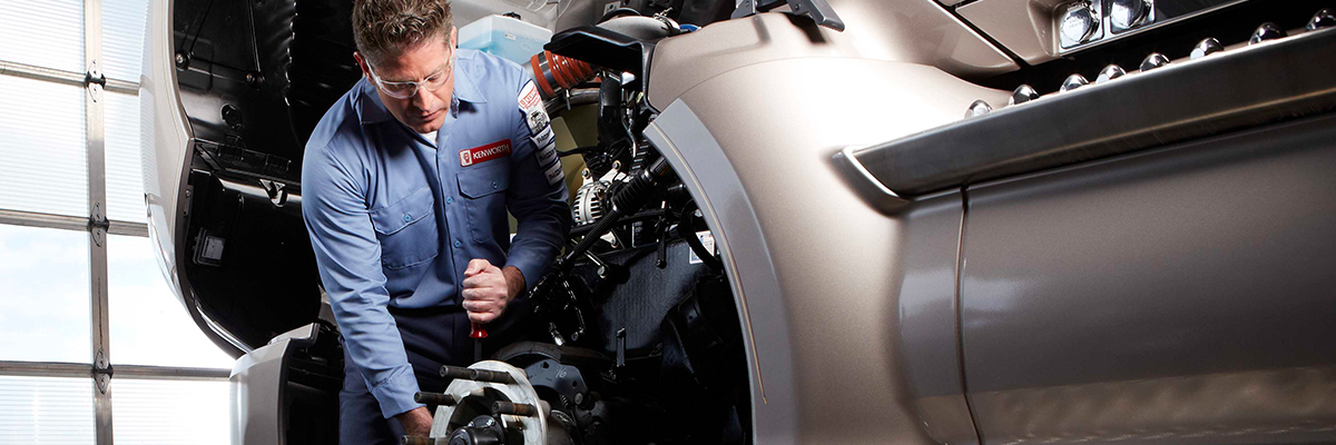 Kenworth technician adjusting brake on truck